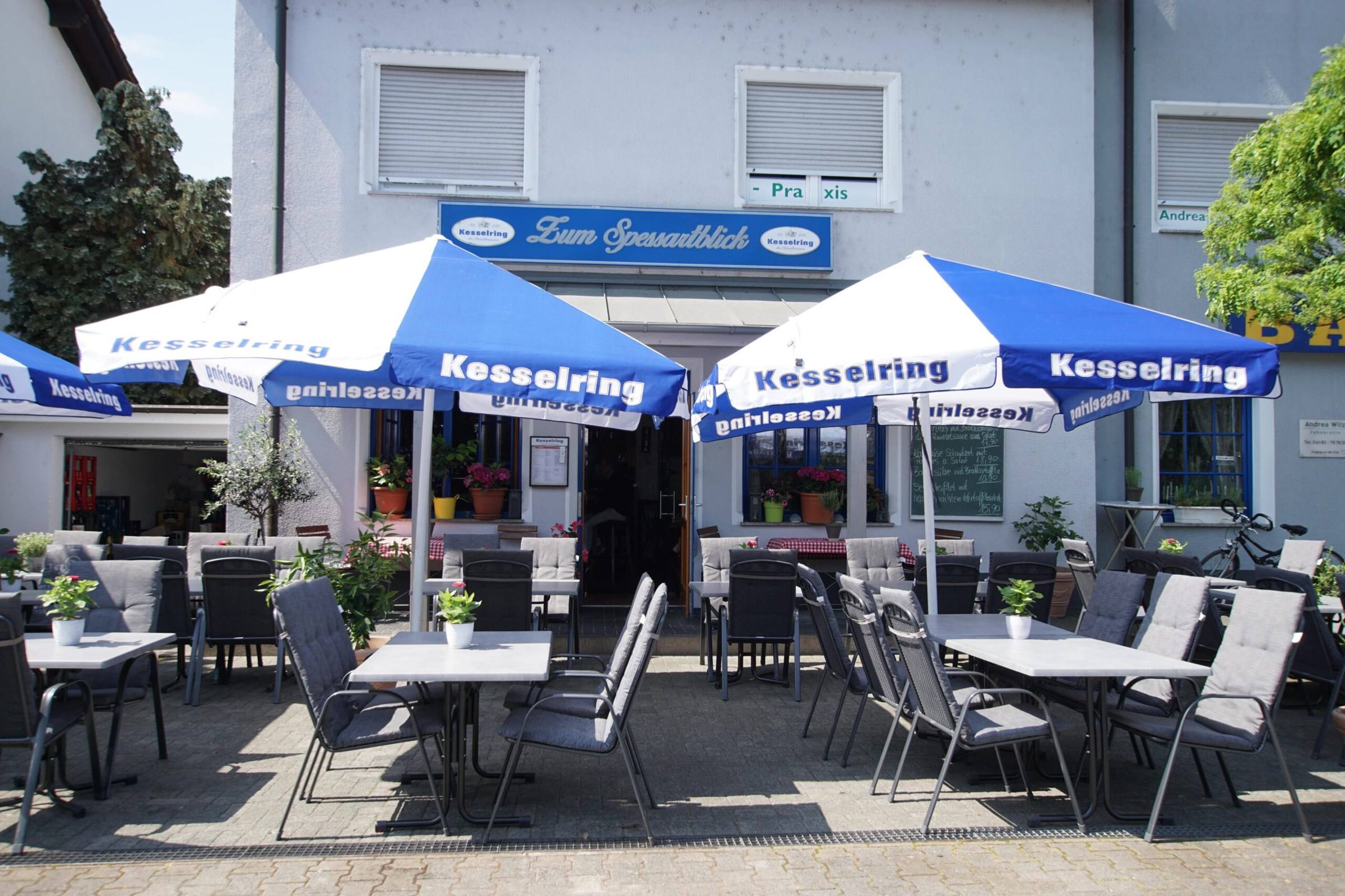 Außenansicht des Restaurants Zum Spessartblick mit Terrasse und blau-weißen Sonnenschirmen